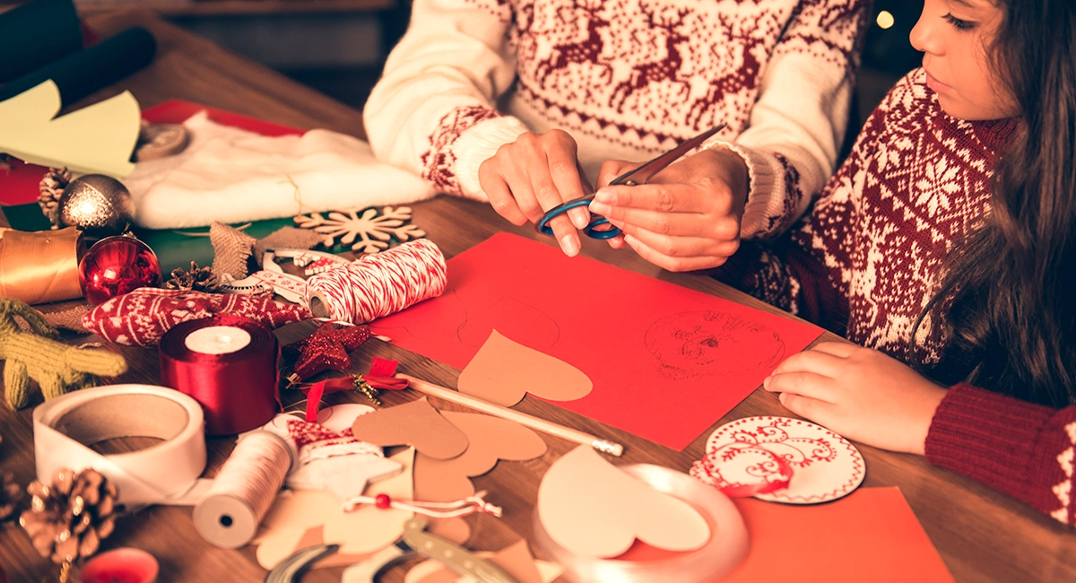 Adult showing kids how to craft Christmas decorations.